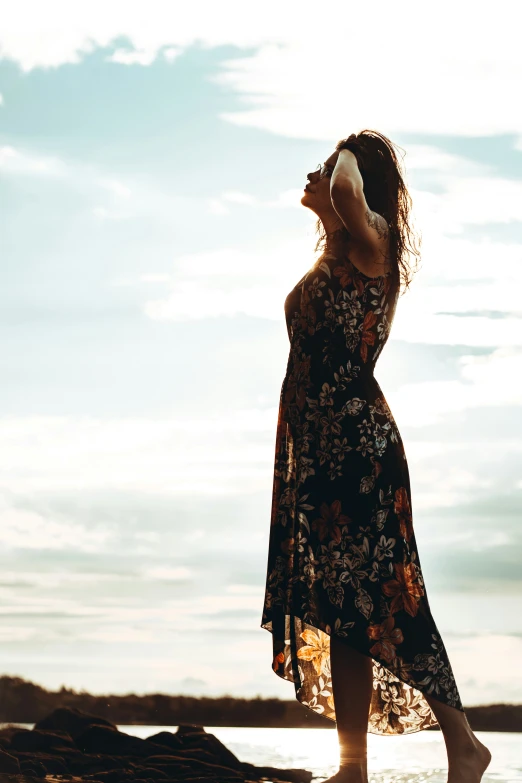 a woman standing on the beach looking up to a sky