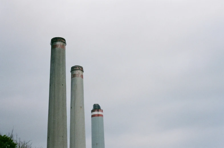 three smoke stacks rise into the sky over a city