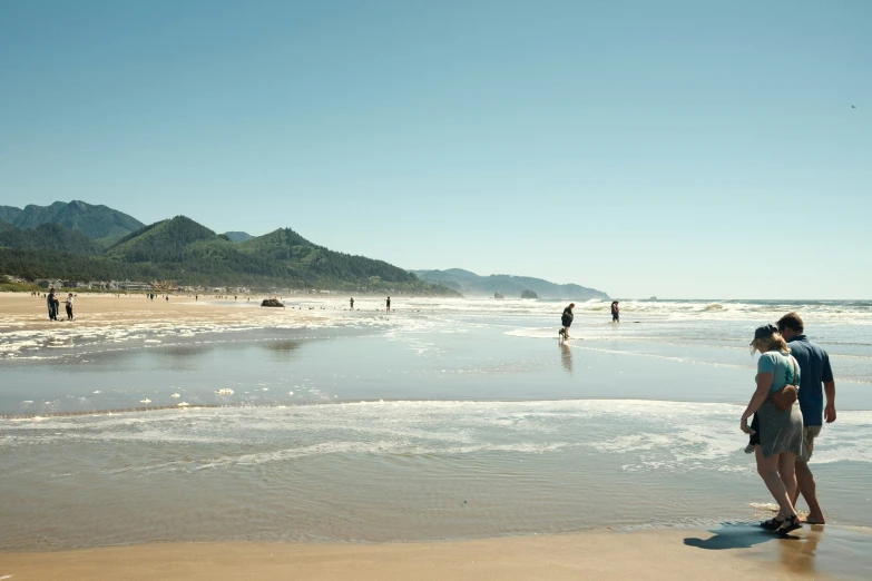 a couple of people walking down a beach next to the ocean