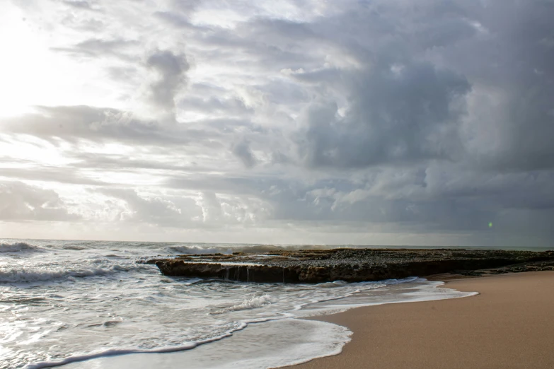 water crashing onto shore and a long jetty on the beach