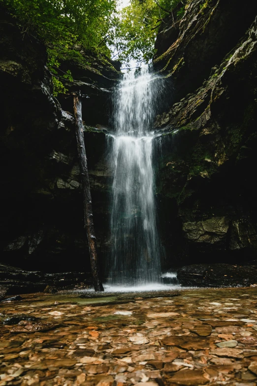 a waterfall is shown surrounded by rocks and green trees