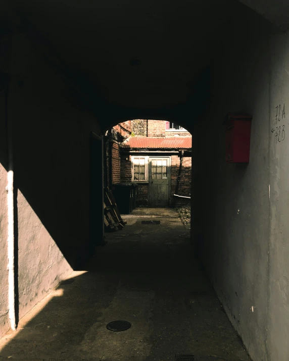 an alley way with a red mailbox next to it