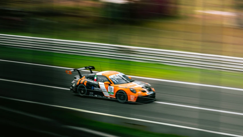 a race car on a track with blurred trees in the background