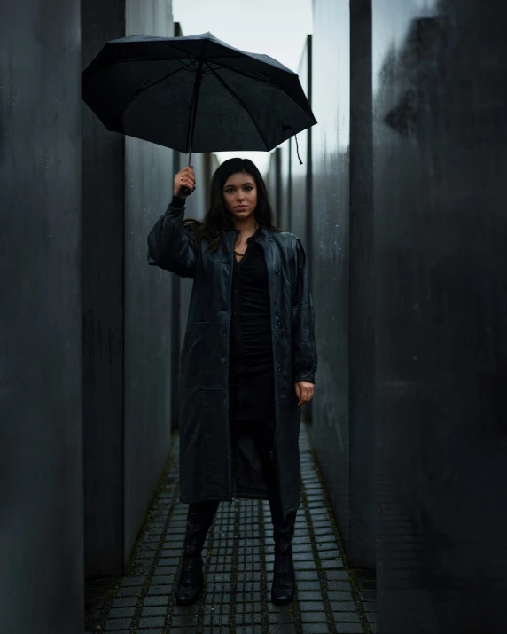 a woman wearing a coat holding a black umbrella