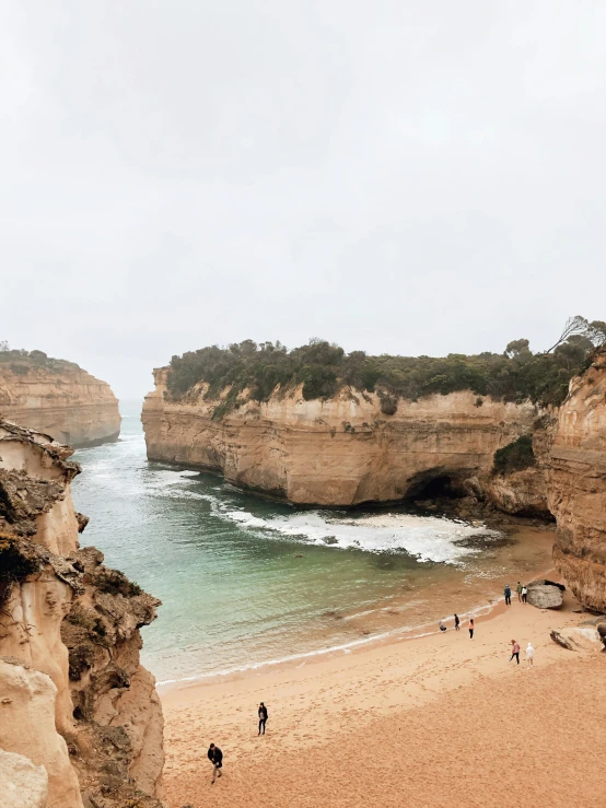 people walking along the beach at an overlook point