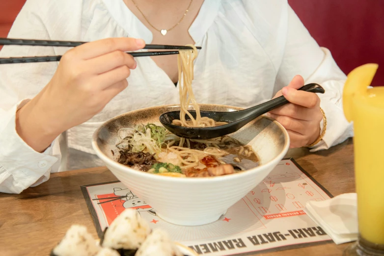 woman eating noodles with chopsticks with chop sticks