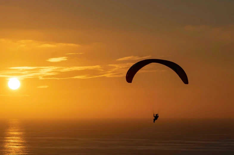 a man is para sailing on a beautiful sunset