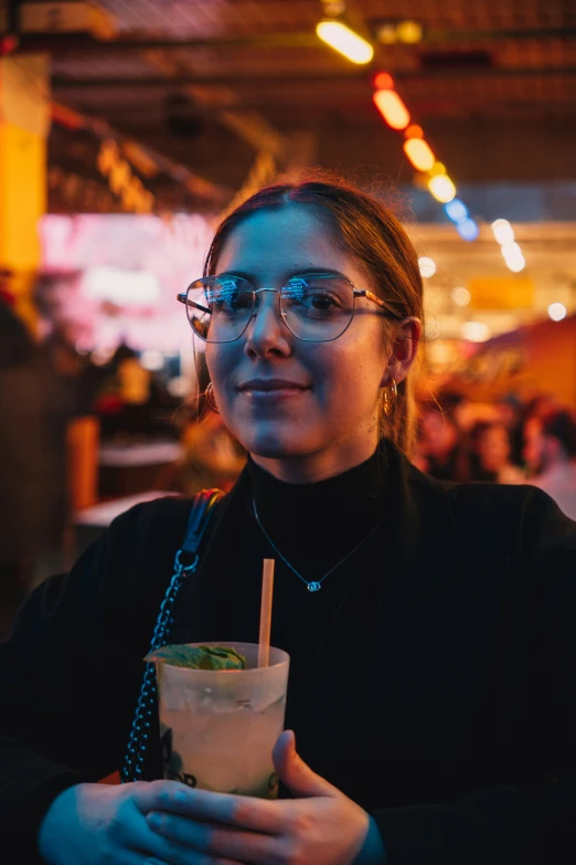 a woman in glasses holding a drink at a bar