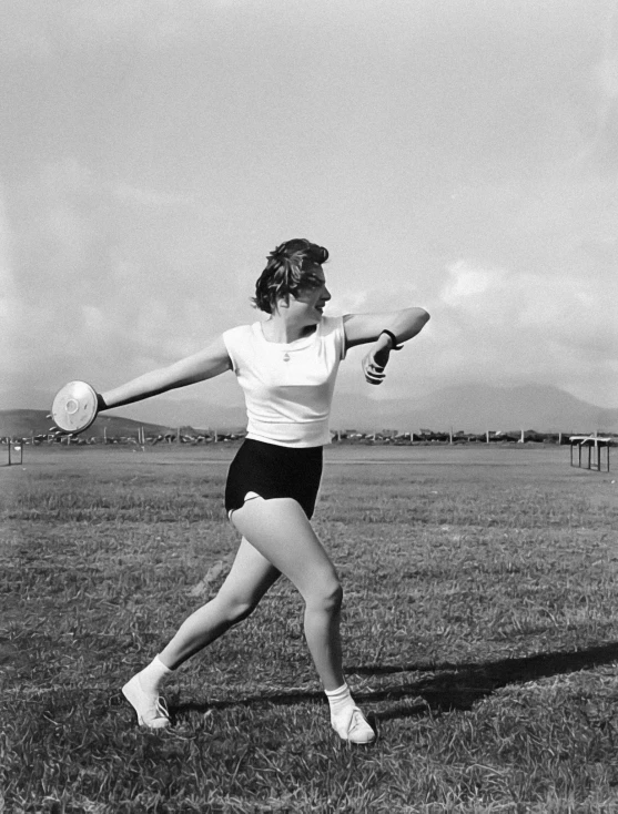 woman with arms extended and holding a white frisbee