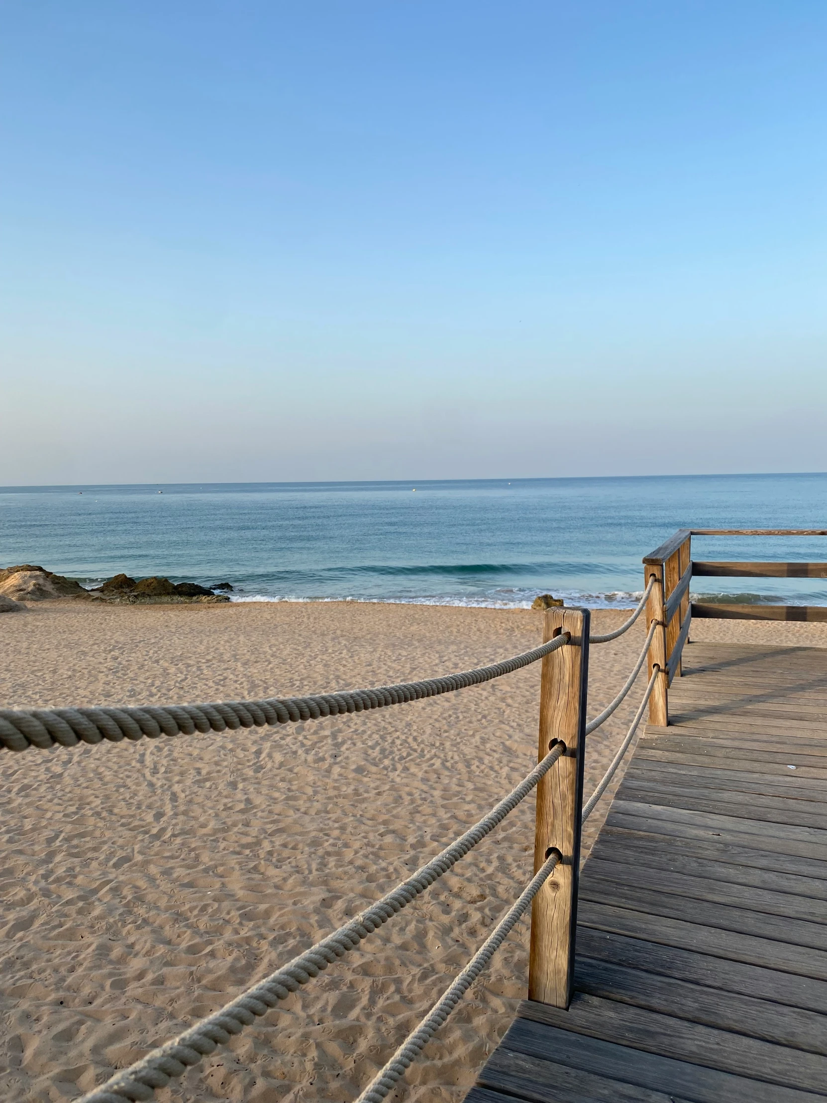 a wooden pathway with wooden posts leads to the ocean