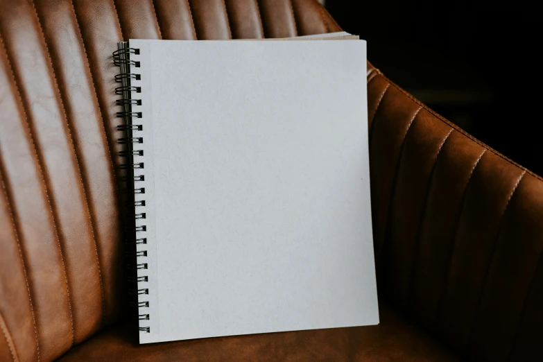 a blank paper sitting on top of a brown leather chair