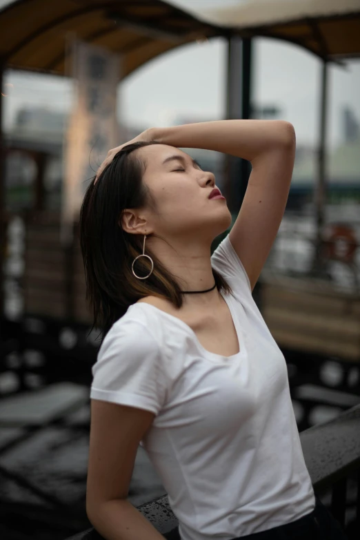 a woman with brown eyes stands with her hands over her head