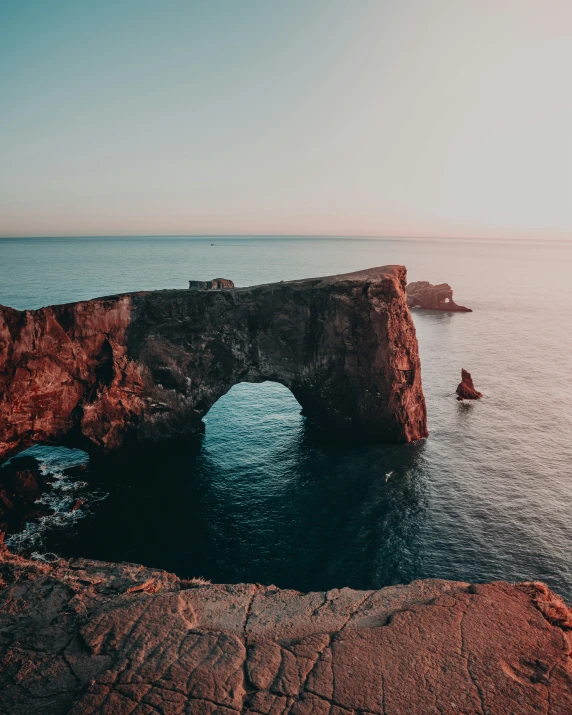 a rock arch is sitting in the middle of an ocean