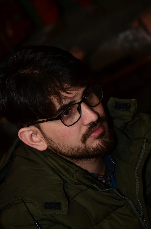 a man with dark hair and glasses looking at soing