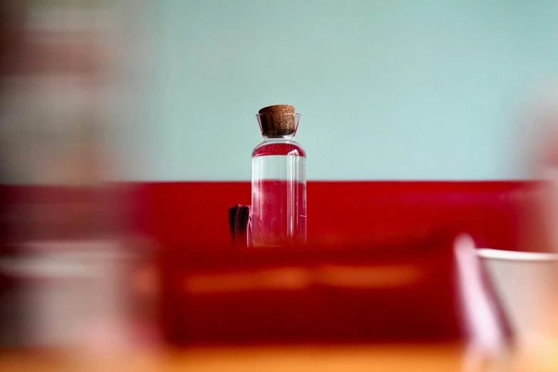 a bottle with red liquid sitting on top of a wooden table