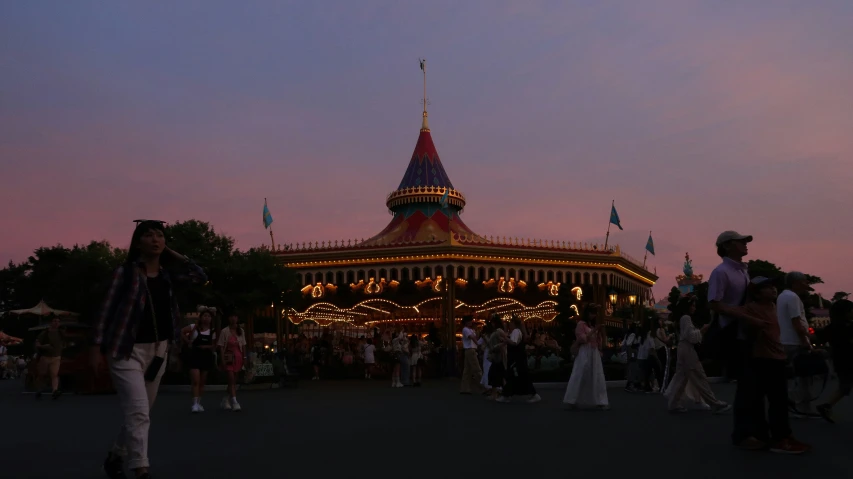 a crowded carnival in the evening with people standing around