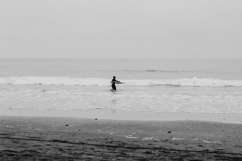 a person standing in the surf while holding a surfboard