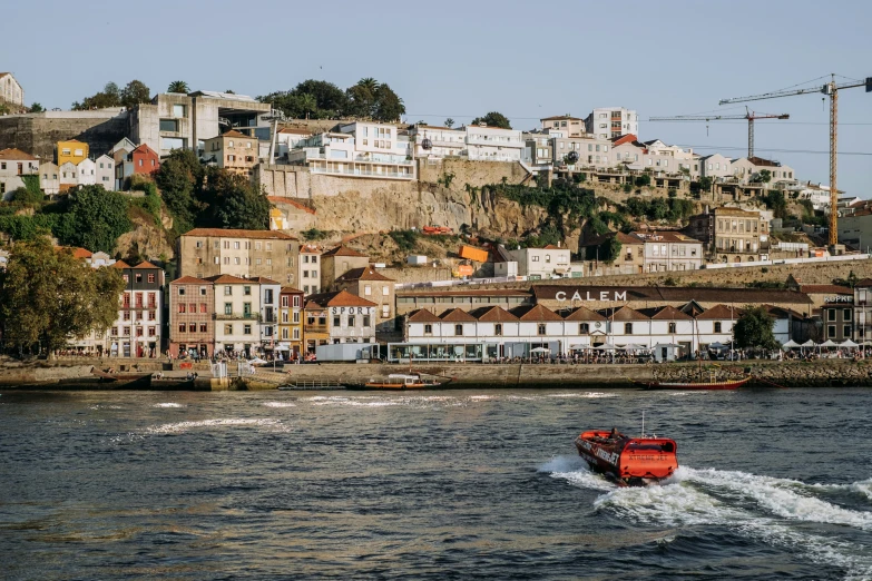 a red boat is in the ocean next to the houses