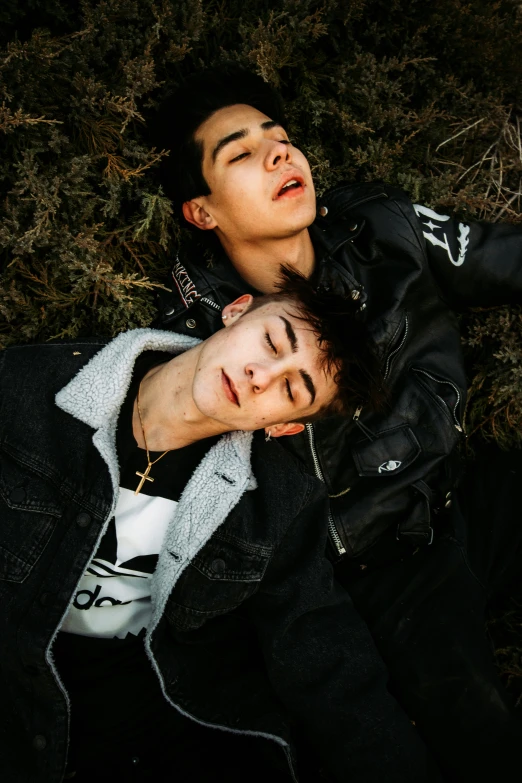 two young men lying on grass staring at the sky