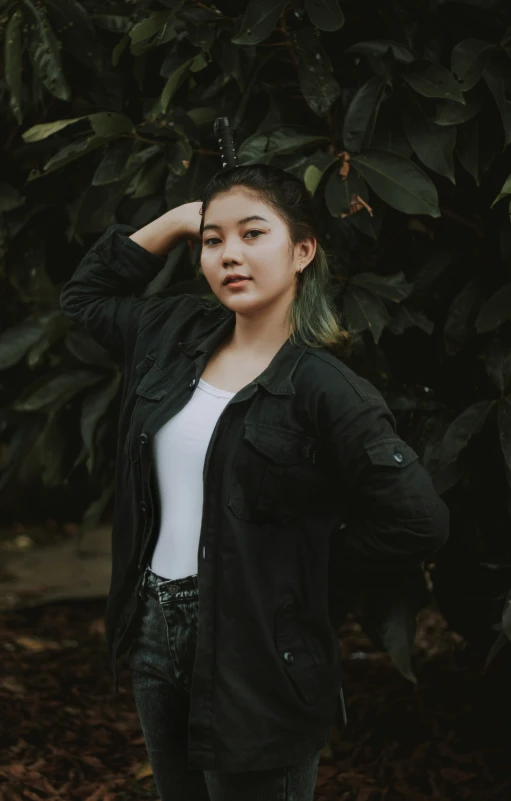 a  posing for the camera, with trees behind her