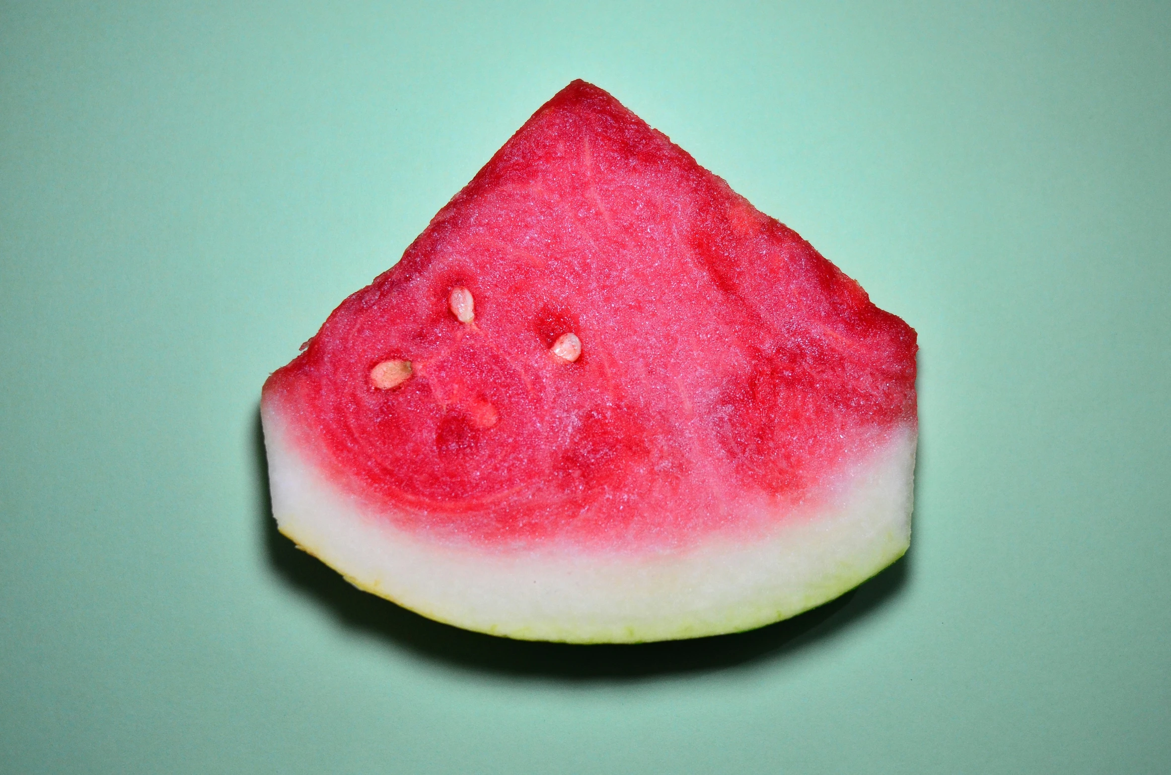 a piece of red fruit sitting on top of a green surface