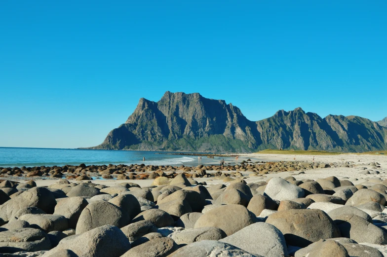 a sandy beach with rocks surrounding the water and a large mountain