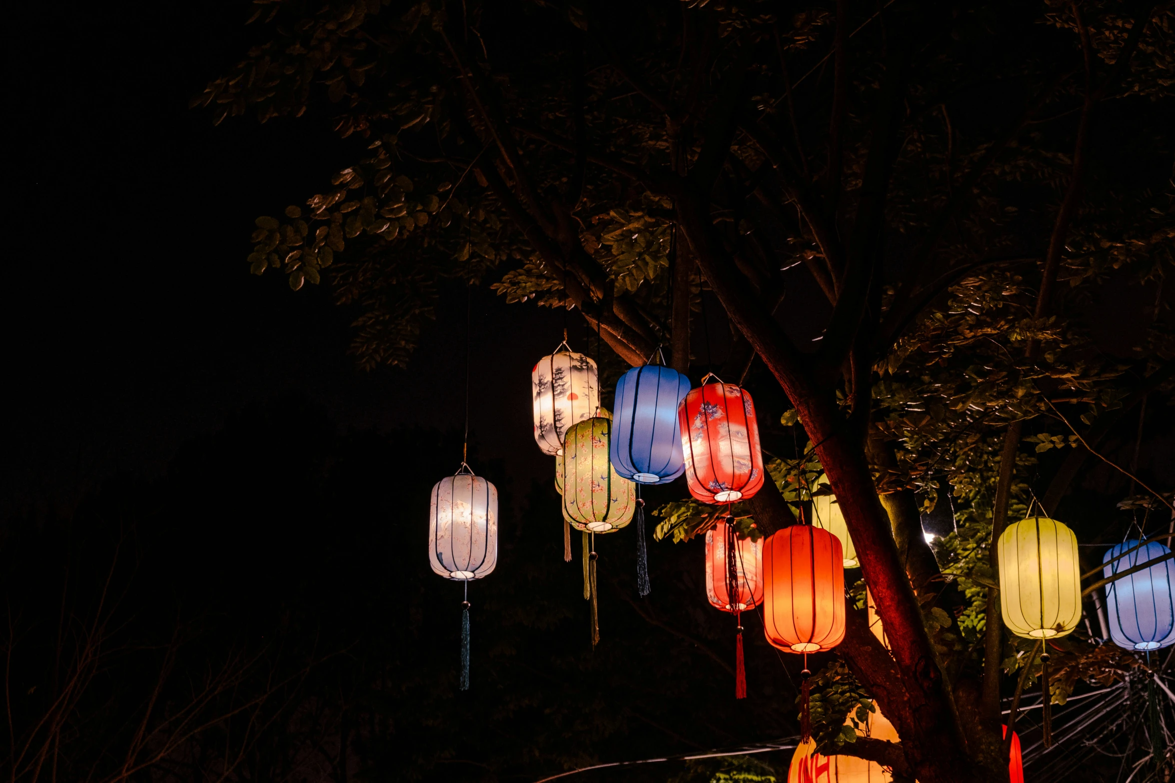 multiple lit paper lanterns are seen at night