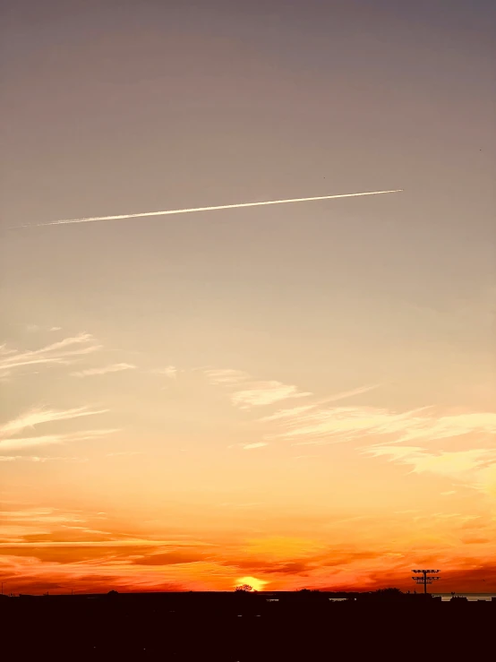 an airplane flies in a clear sunset sky