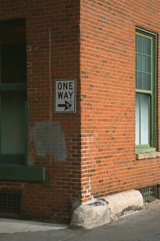 a one way sign on a red brick building