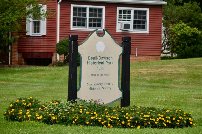 a wooden sign sitting in the grass near flowers