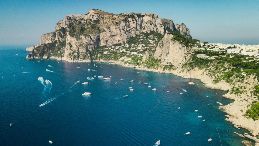 yachts anchored in the open blue water near a white sand beach