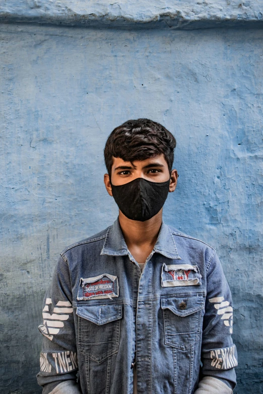 a man wearing a face mask against a blue wall