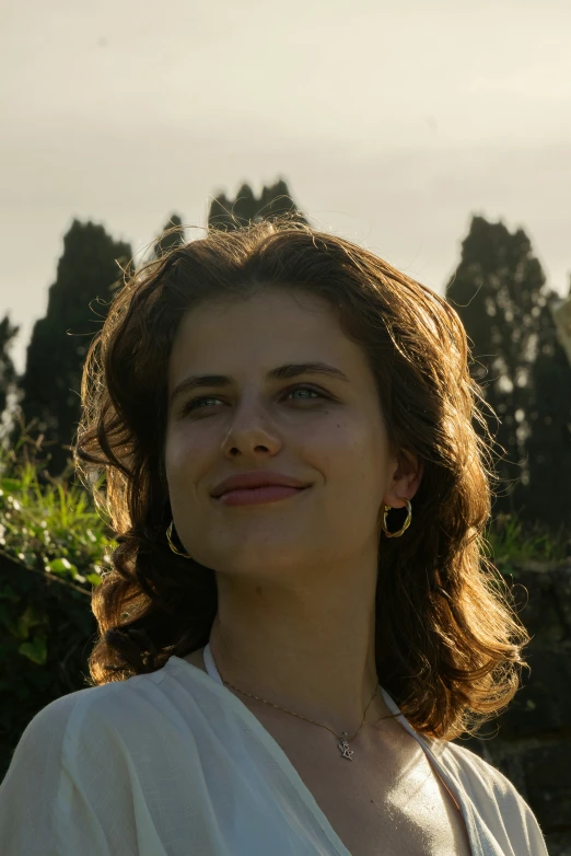 a woman in white top smiling with trees in the background