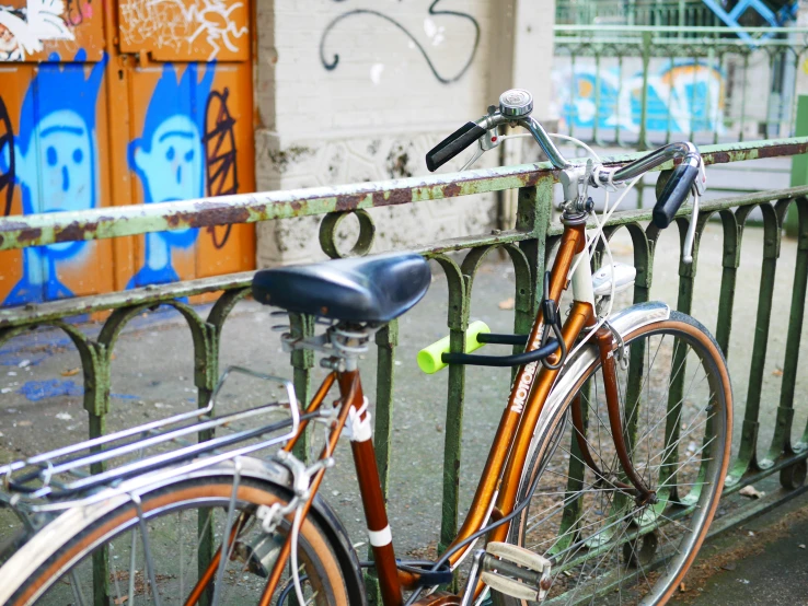 the bike is leaning against a metal fence