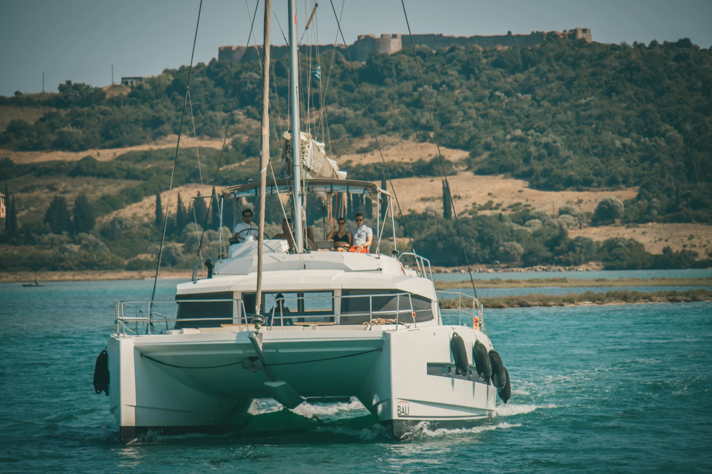 a white catamaran sailing on a body of water