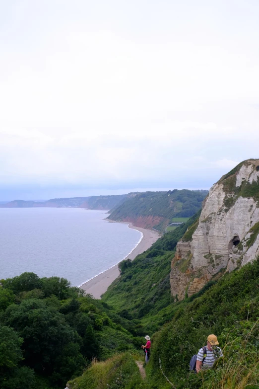 people climbing a hill near a beach area