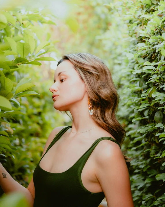 a woman standing near a bush of green bushes and holding soing