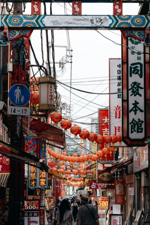 a busy asian street with a lot of colorful and hanging decorations