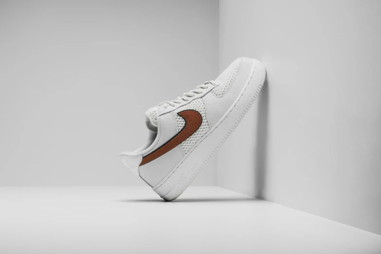 a pair of white nike shoes with brown accents