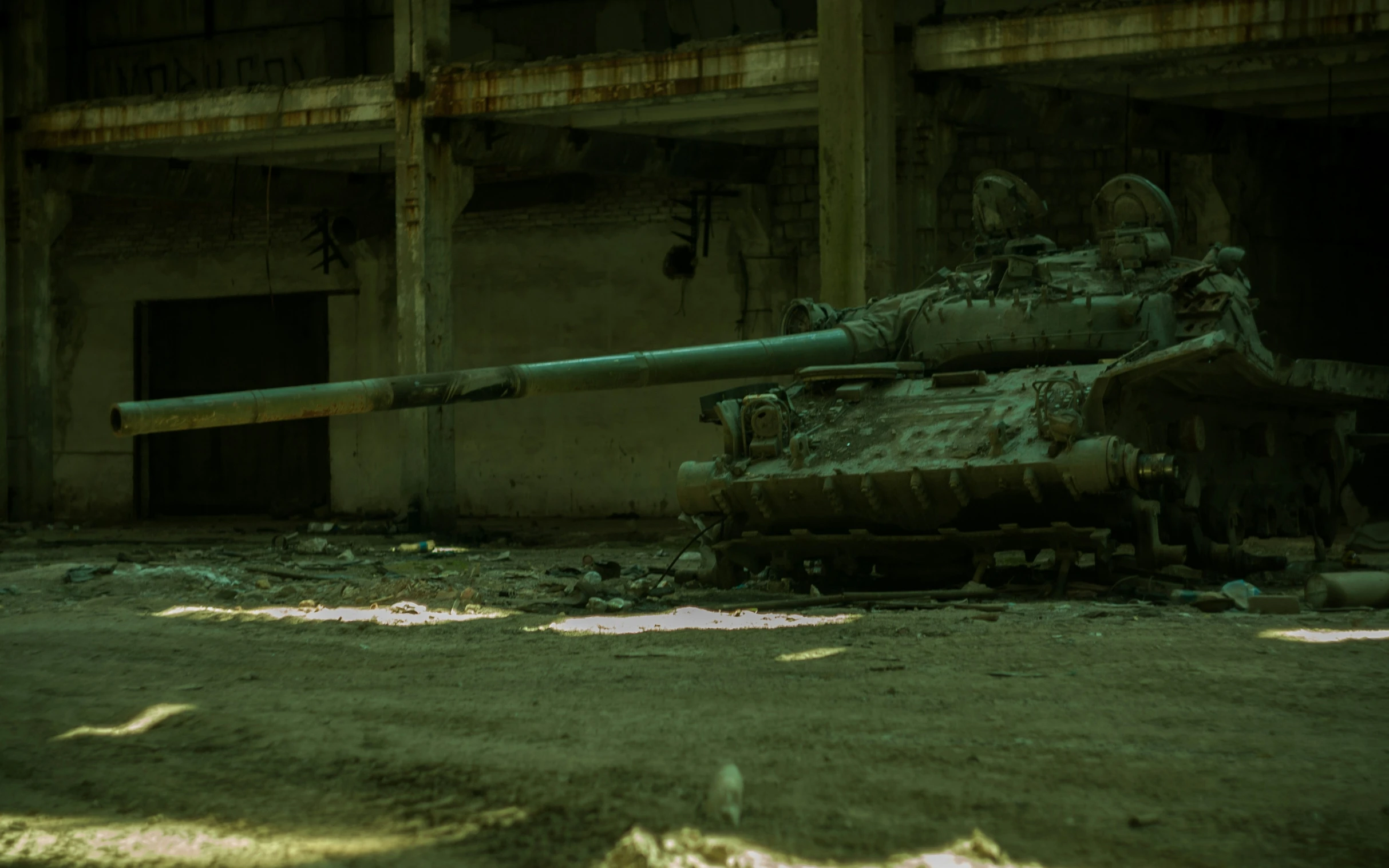 a small army tank sits in the middle of an abandoned warehouse