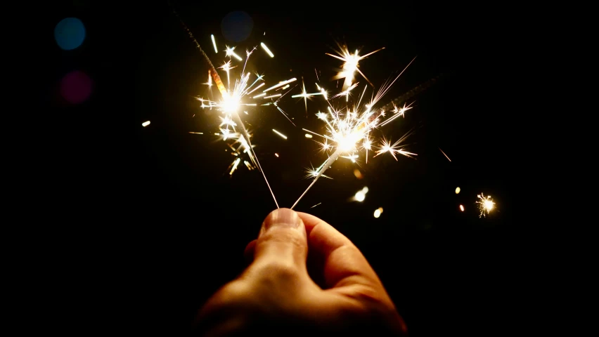 a person is holding a small sparkler in the dark