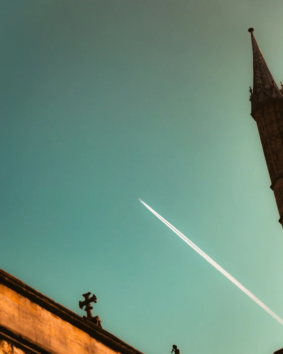 an airplane flies high in the sky near a building