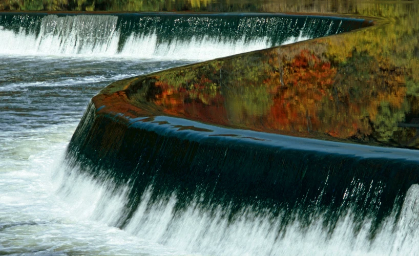 a water fall surrounded by brown and green plants