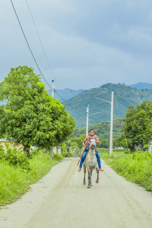 a man on horseback is riding down a dirt road