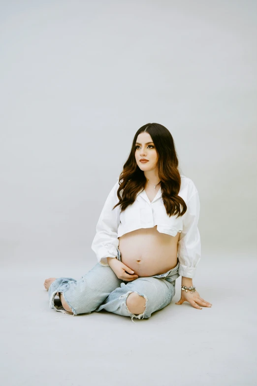 a pregnant woman sitting on the ground