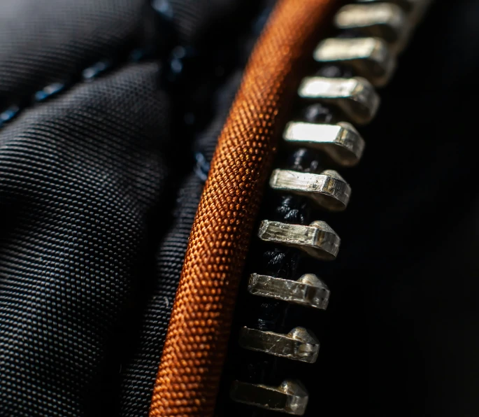a close up of a metal zipper with an orange ring