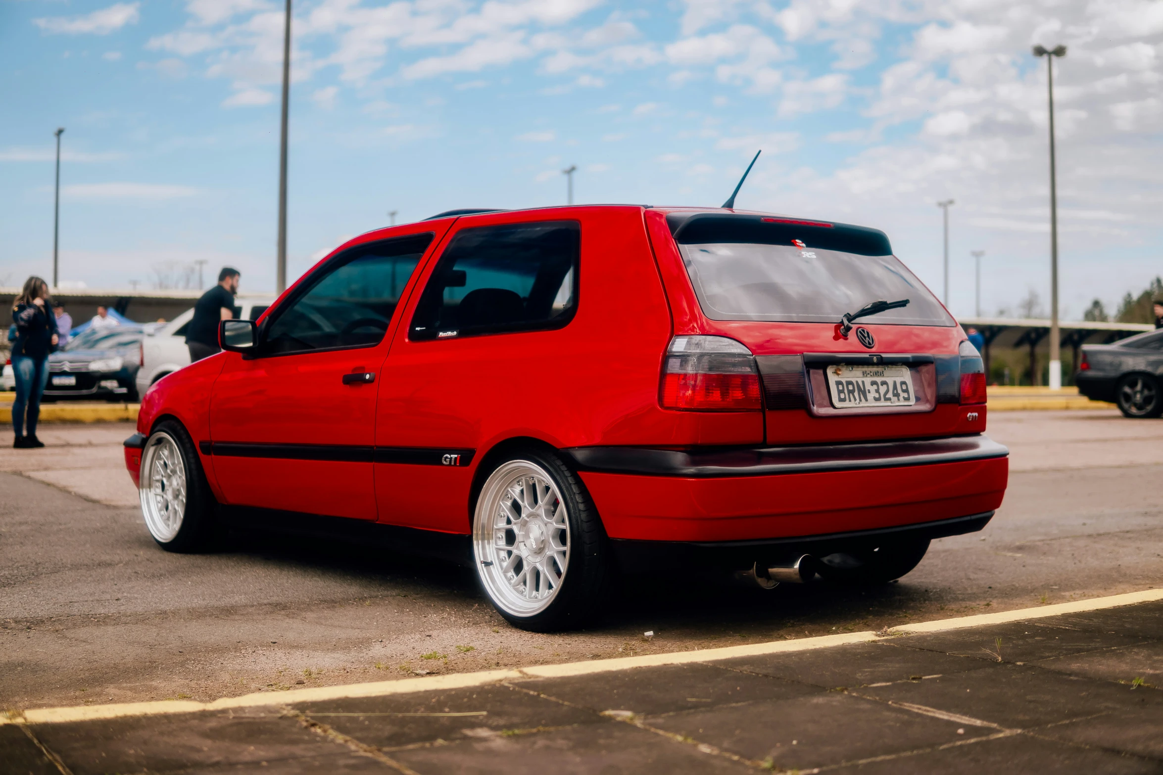 the back end of a red car parked in a parking lot