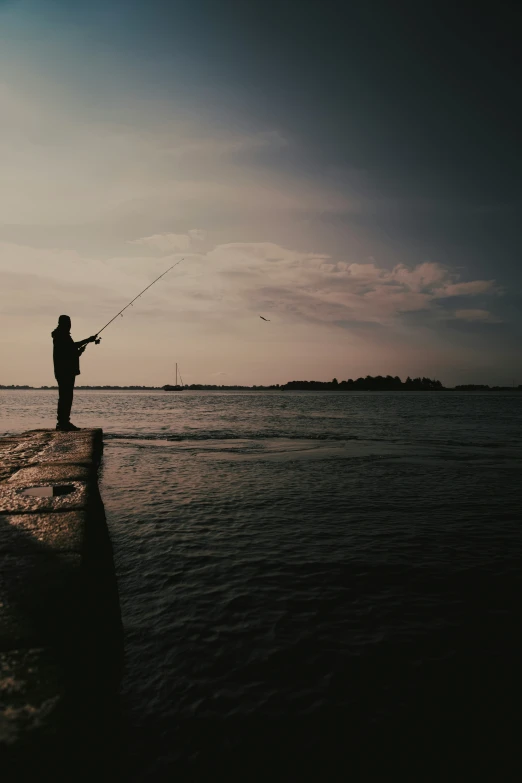 a person fishing in the ocean with a sky background