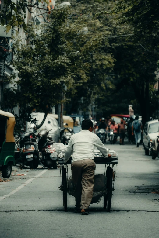 a man riding on the back of a bicycle down a city street