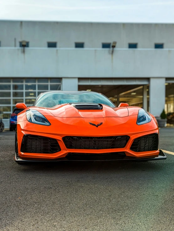 the orange sports car is parked in front of a building